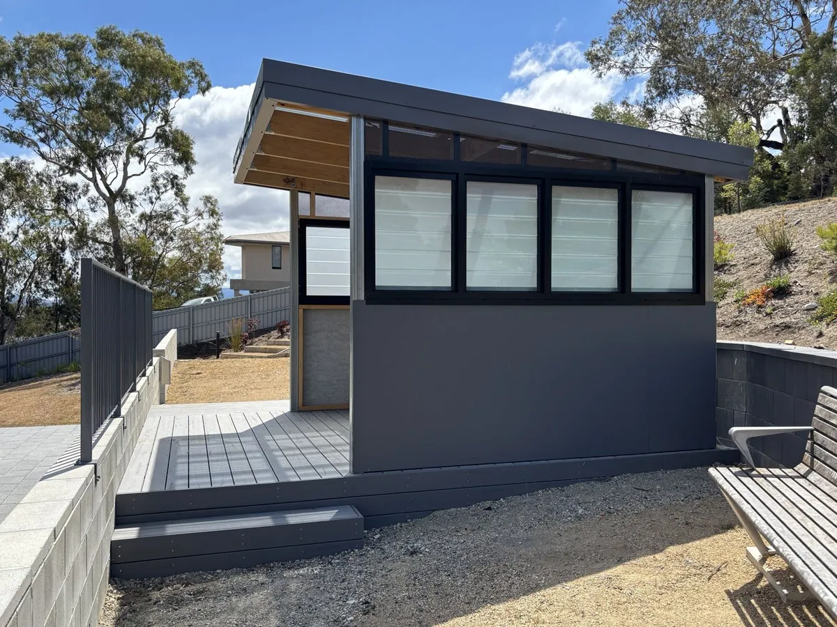Covered deck and studio being finished at a community housing development, hills behind