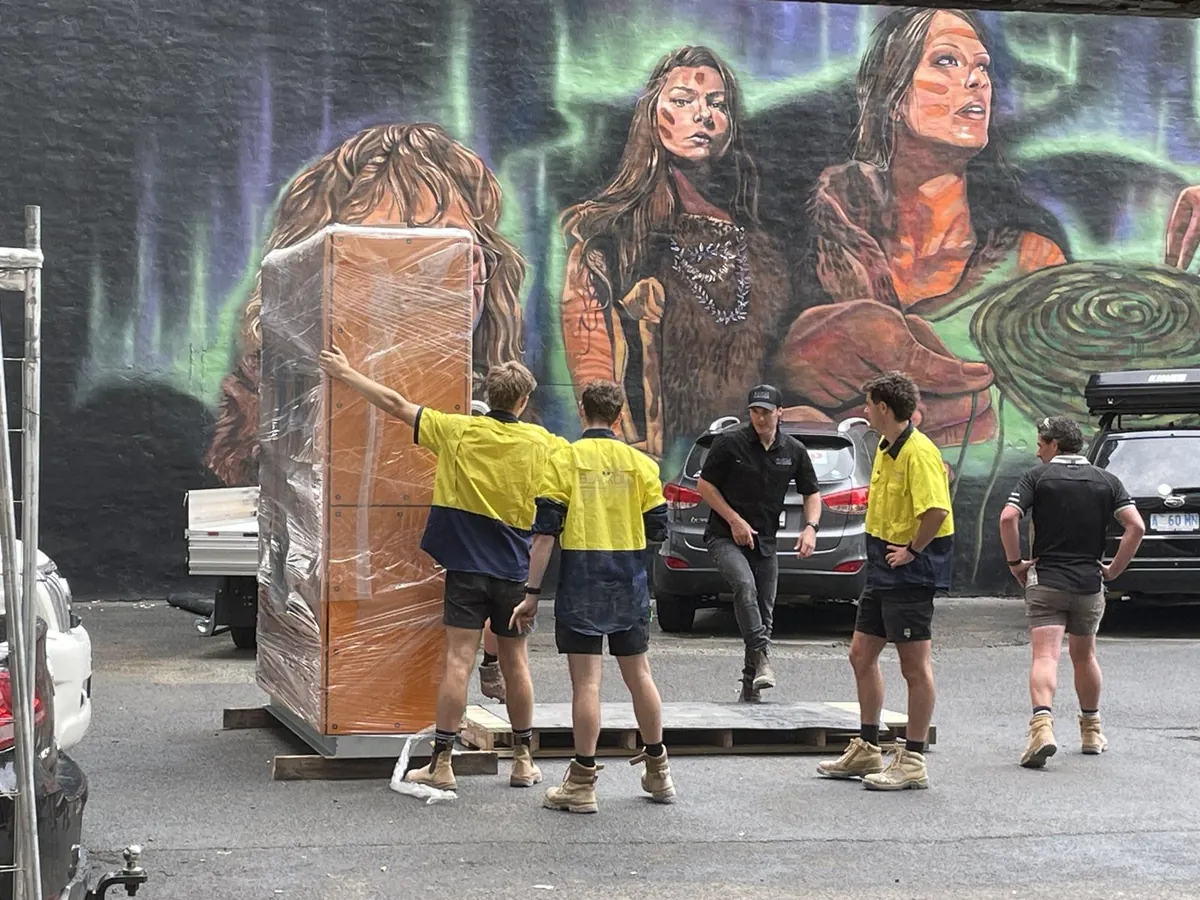 Allen Built crew in high-vis moving a crated switchboard at the State Library of Tasmania